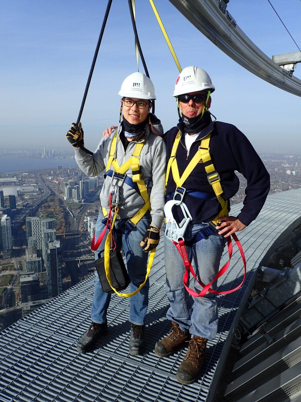 Two people wearing harnesses standing on top of building